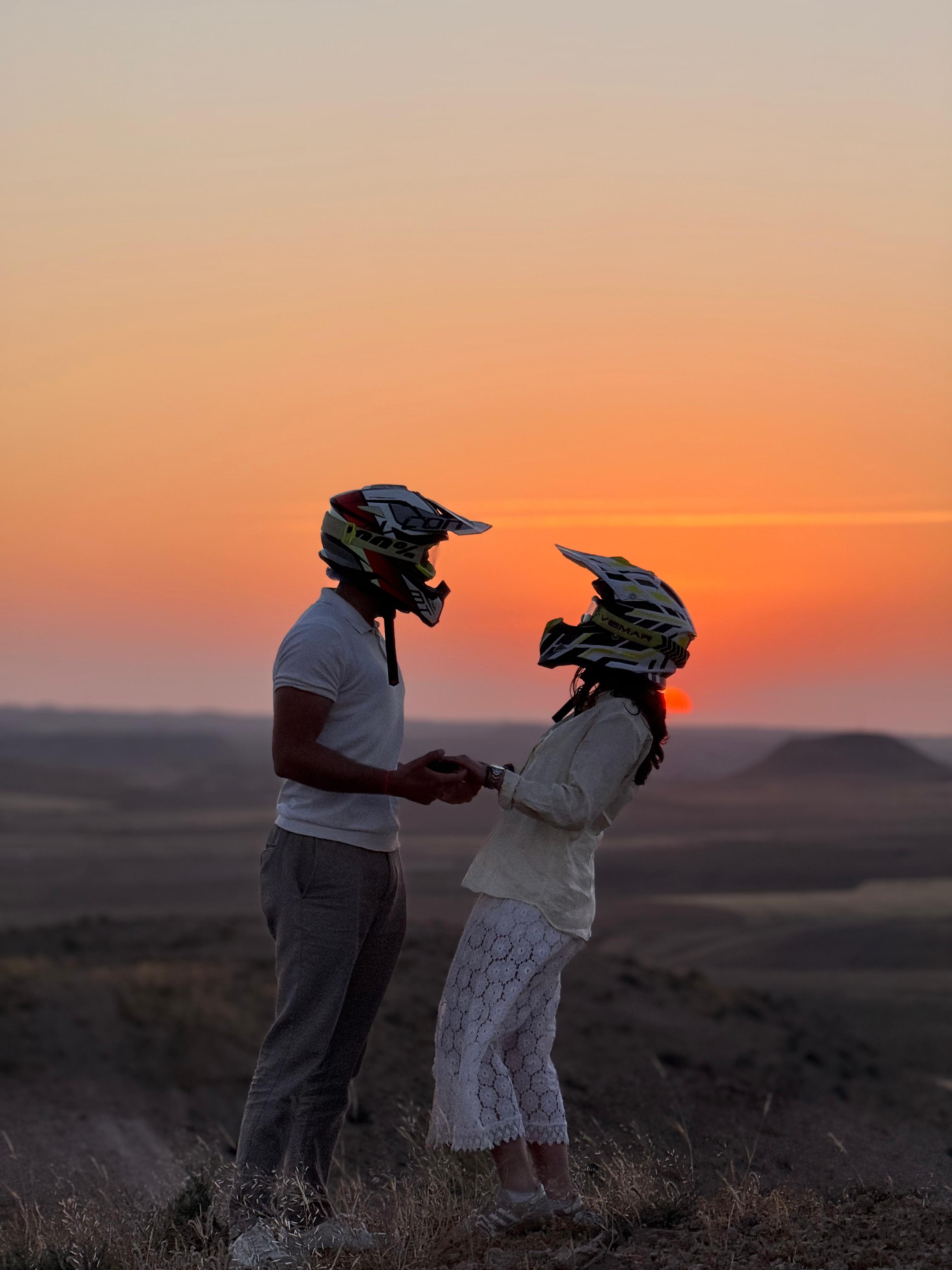 Couple en casque cross face au coucher de soleil dans le désert d'Agafay