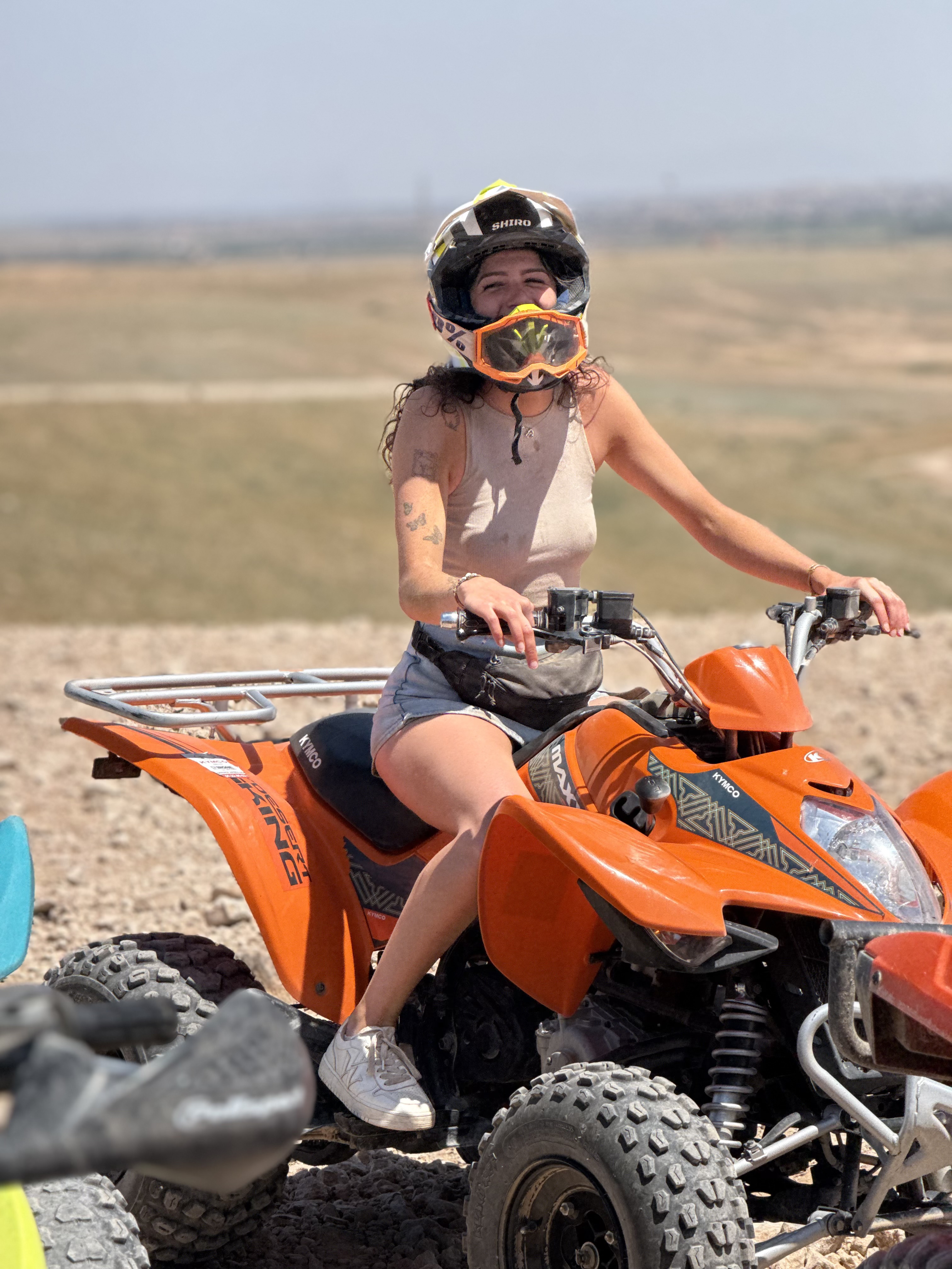 Pilote souriante sur un quad Kymco orange dans le désert d'Agafay